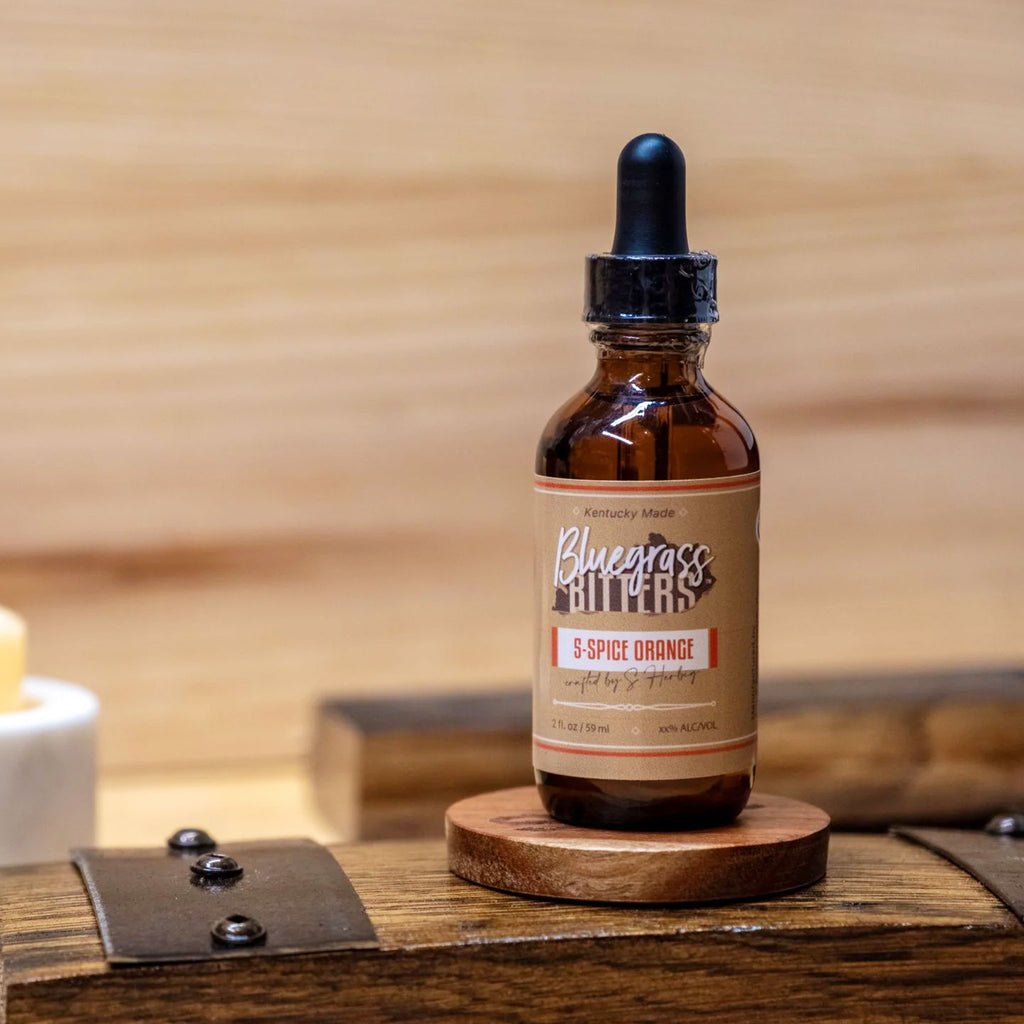 Bluegrass Bitters 5-Spice Orange Bitters on a wooden surface with a wooden background