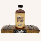 Bottle of Bluegrass Bitters Smoky Simple Syrup on a wooden stave display against a white background