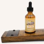 Bottle of Bluegrass Bitters 5-Spice Orange Bitters on a wooden stave display against a white background